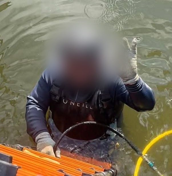 Endeavor diver at the surface wearing a mask, lights, and camera equipment